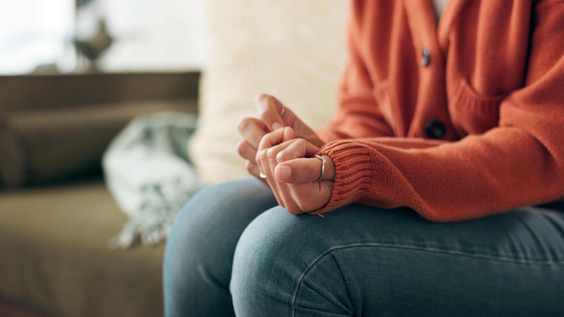 woman's torso sitting on bench clutching her hands